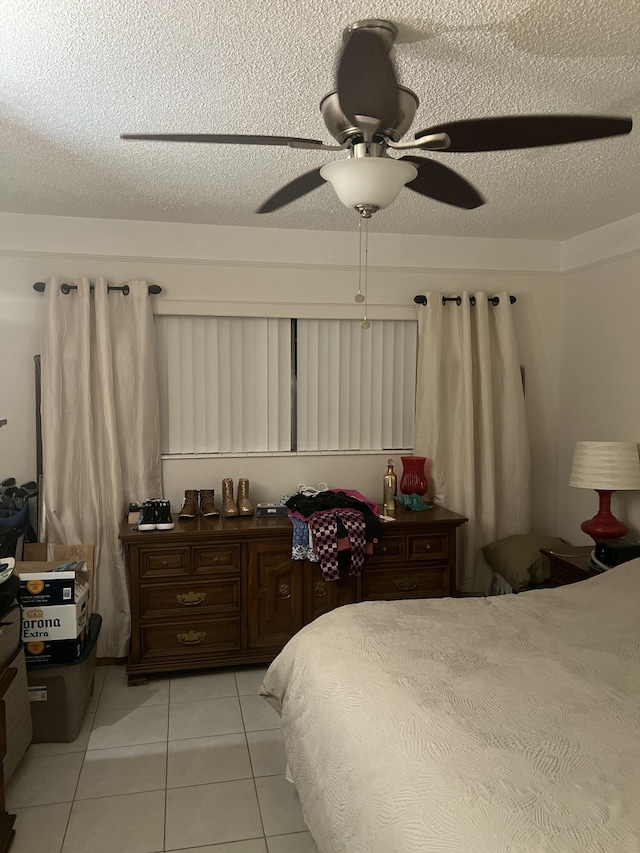 bedroom with light tile patterned floors, ceiling fan, and a textured ceiling