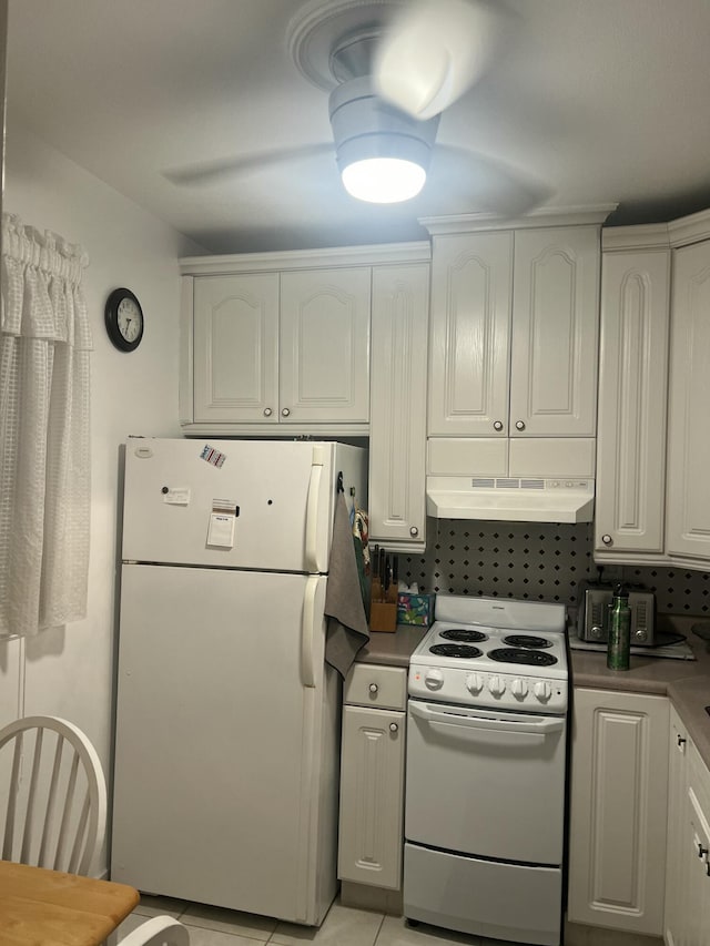 kitchen with dark countertops, white appliances, white cabinetry, and under cabinet range hood