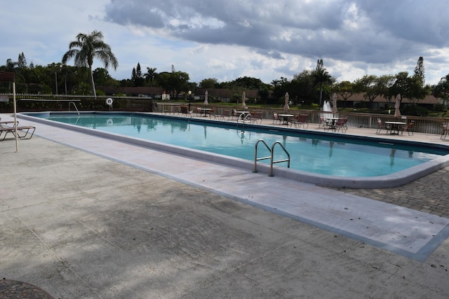 pool with a patio area and fence