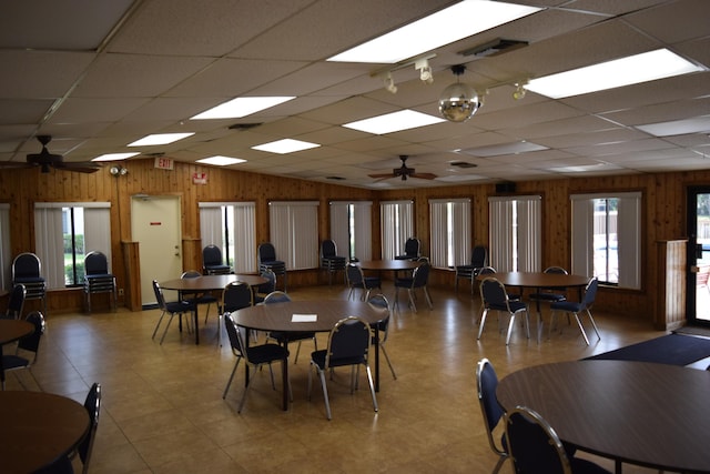 dining space featuring wooden walls, visible vents, ceiling fan, vaulted ceiling, and a paneled ceiling