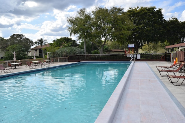 pool with a patio area and fence