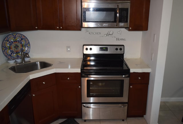 kitchen with stainless steel appliances, light countertops, a sink, and light tile patterned floors