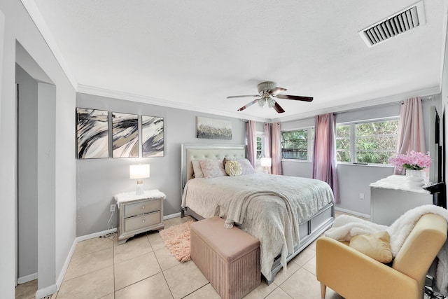 bedroom with light tile patterned floors, visible vents, baseboards, and crown molding