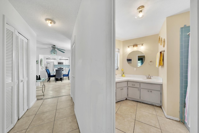 bathroom with tile patterned flooring, ceiling fan, a closet, and a sink