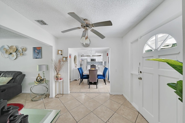 entryway featuring light tile patterned floors, visible vents, a textured ceiling, and a ceiling fan