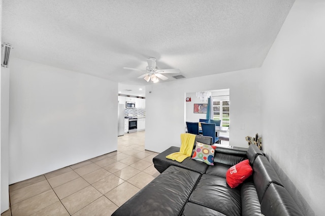 living area with visible vents, a textured ceiling, light tile patterned flooring, and a ceiling fan