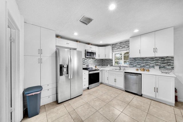 kitchen with visible vents, backsplash, light countertops, stainless steel appliances, and a sink