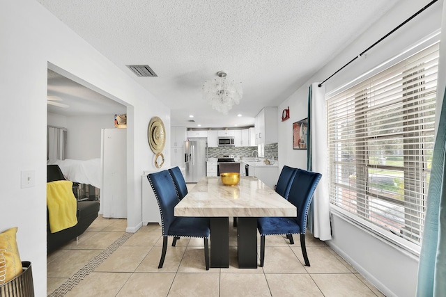 dining space with visible vents, a textured ceiling, an inviting chandelier, and light tile patterned flooring