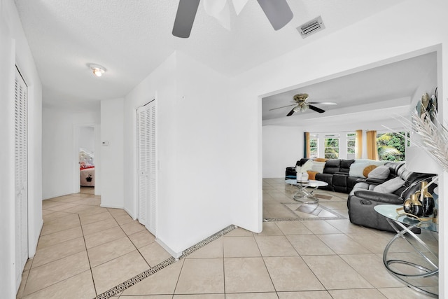 hall featuring light tile patterned floors, visible vents, and a textured ceiling