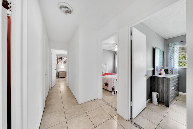 hall with light tile patterned floors and a textured ceiling