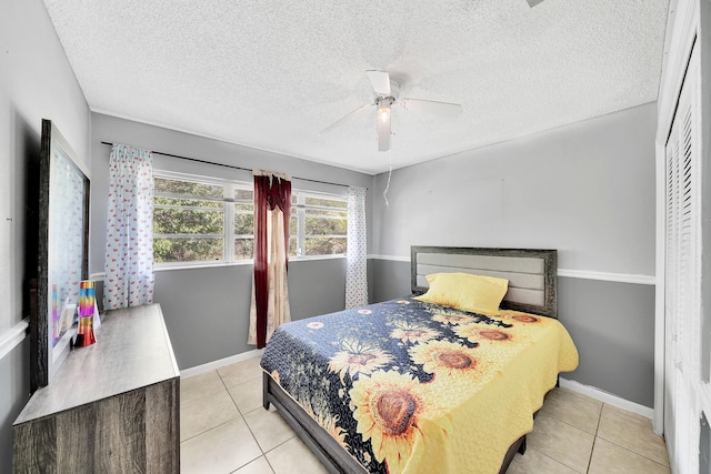 bedroom with light tile patterned floors, ceiling fan, a textured ceiling, and baseboards