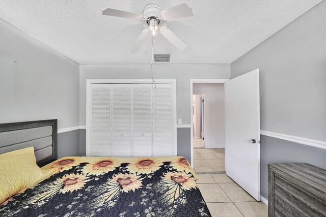 bedroom featuring light tile patterned floors, visible vents, a closet, and a textured ceiling