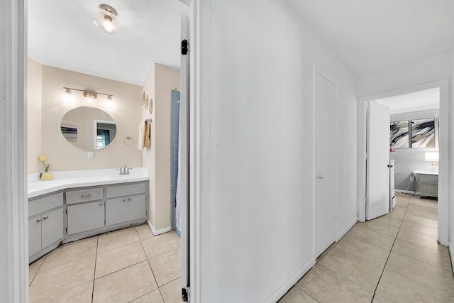 hallway with a sink, baseboards, and light tile patterned floors