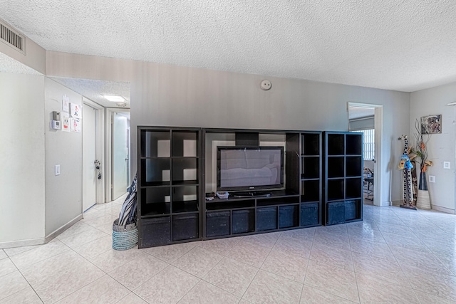 living room with light tile patterned floors, a textured ceiling, visible vents, and baseboards