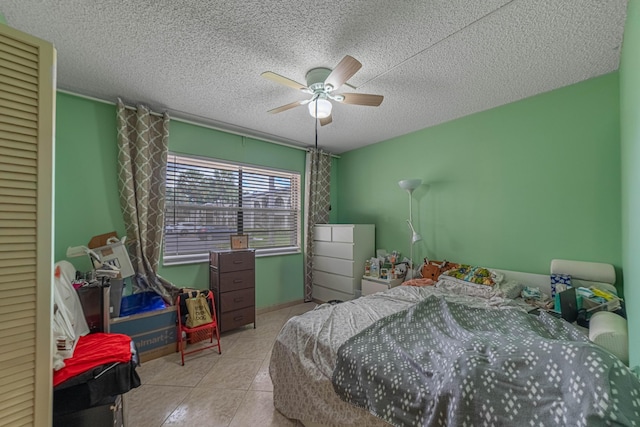 bedroom with a ceiling fan, light tile patterned flooring, and a textured ceiling