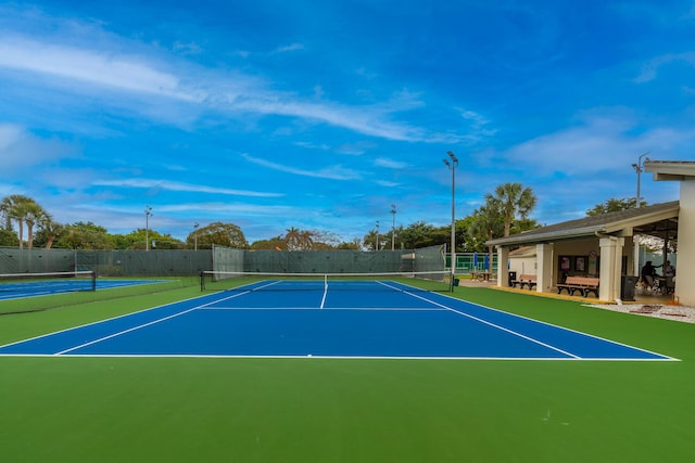 view of tennis court with community basketball court and fence