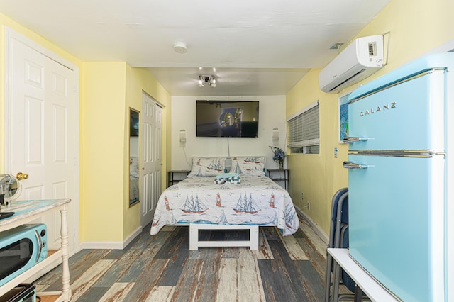 bedroom with a wall mounted AC, baseboards, dark wood-style flooring, and freestanding refrigerator