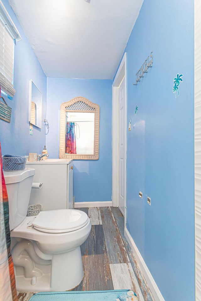 bathroom with wood finished floors, toilet, and baseboards