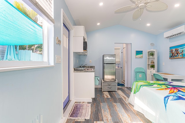 kitchen with lofted ceiling, a wall mounted AC, dark wood-type flooring, freestanding refrigerator, and white cabinets