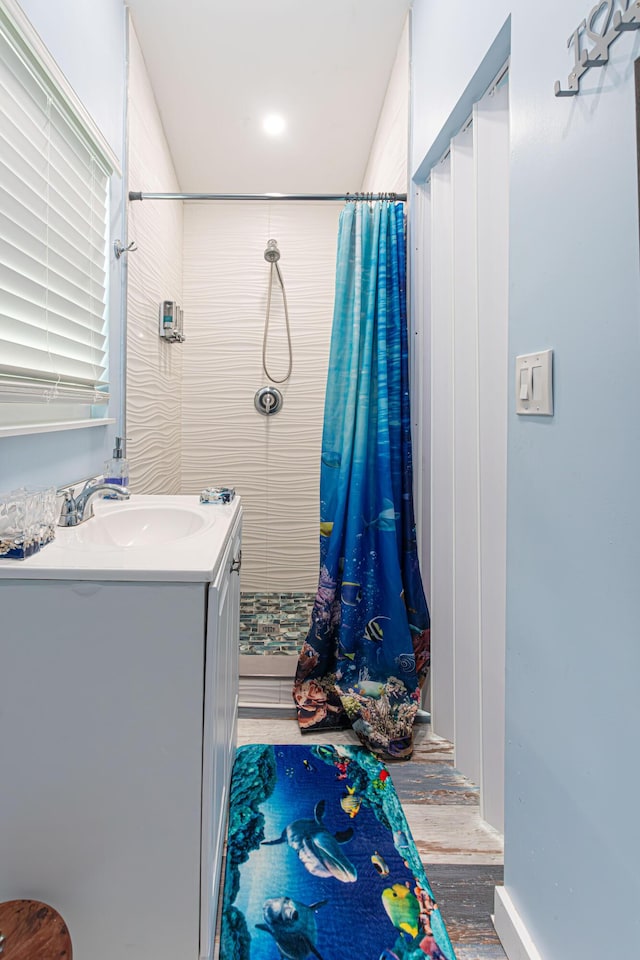 full bathroom featuring a stall shower, vanity, and wood finished floors