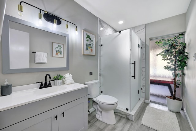 bathroom featuring recessed lighting, toilet, a stall shower, and vanity