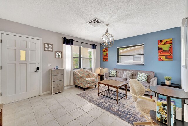 living room with visible vents, stacked washer / dryer, light tile patterned floors, baseboards, and a chandelier