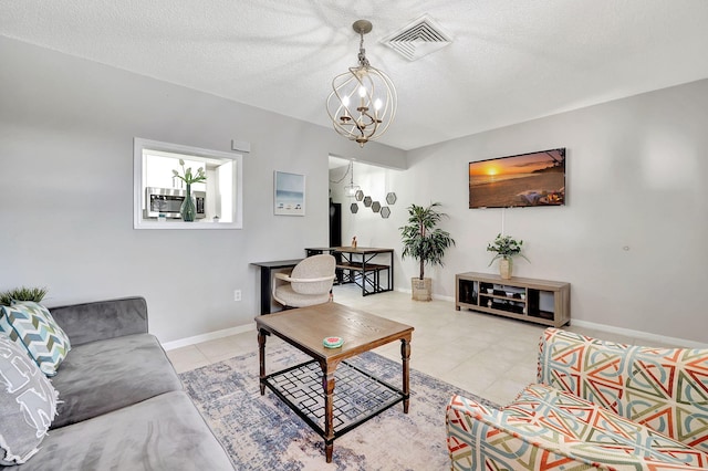 living room featuring visible vents, baseboards, light tile patterned floors, an inviting chandelier, and a textured ceiling