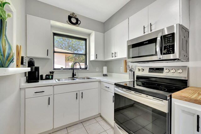 kitchen with white cabinetry, stainless steel appliances, light countertops, and a sink