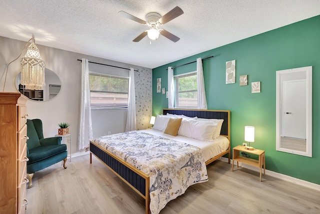 bedroom featuring a textured ceiling, a ceiling fan, baseboards, and wood finished floors