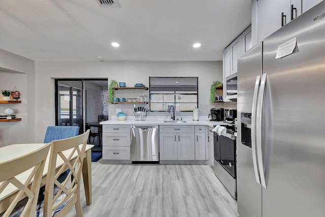 kitchen with open shelves, light wood-style flooring, a wealth of natural light, and stainless steel appliances