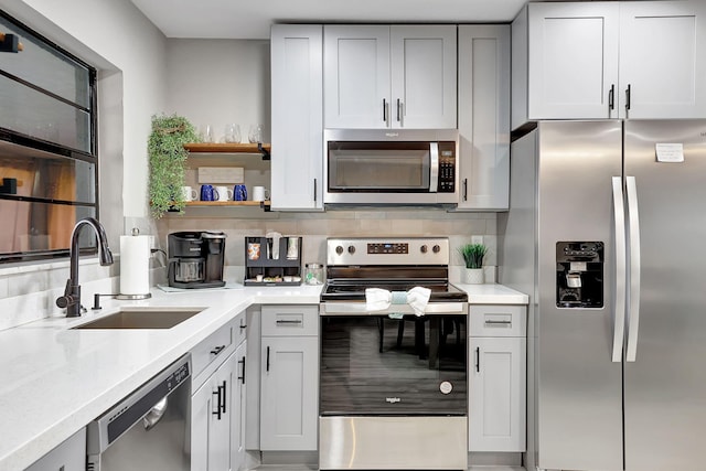 kitchen featuring a sink, light countertops, tasteful backsplash, and stainless steel appliances