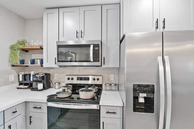 kitchen with open shelves, tasteful backsplash, white cabinetry, appliances with stainless steel finishes, and light countertops