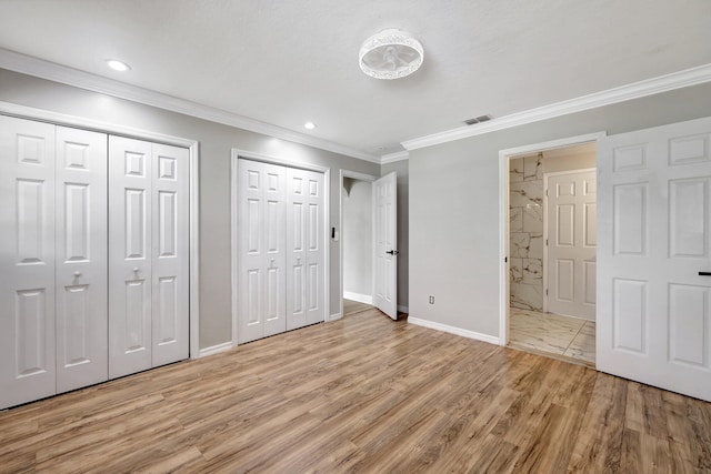 unfurnished bedroom featuring visible vents, light wood-style flooring, baseboards, and multiple closets