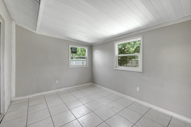 spare room featuring light tile patterned floors, baseboards, and lofted ceiling