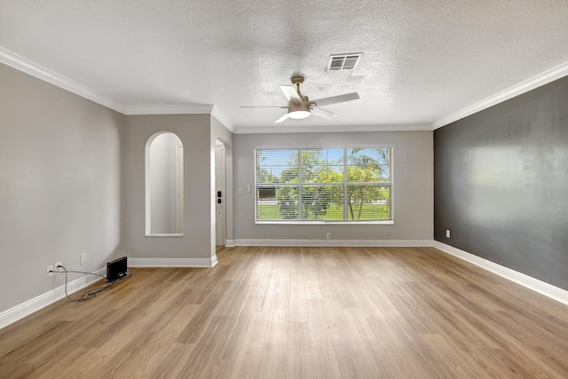 spare room featuring visible vents, light wood-style flooring, a ceiling fan, crown molding, and baseboards