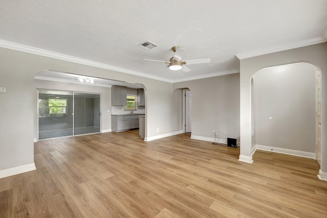 unfurnished living room with arched walkways, visible vents, and a ceiling fan