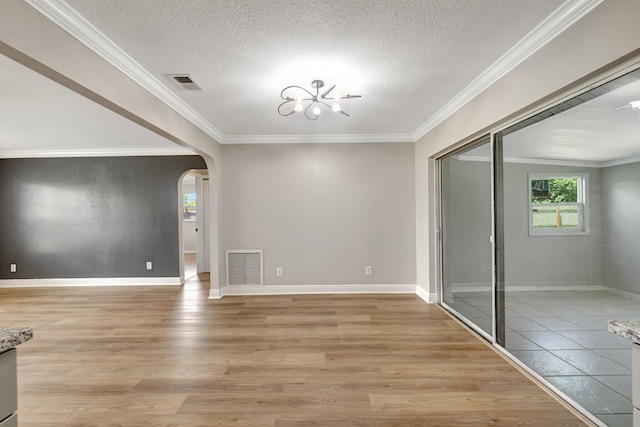 interior space featuring visible vents, light wood finished floors, arched walkways, ornamental molding, and a notable chandelier