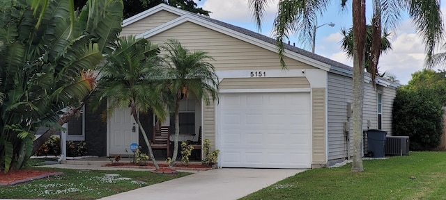 view of front of home with central AC, a front lawn, and an attached garage