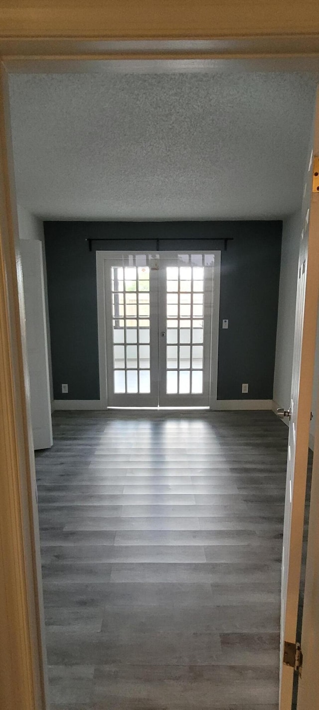 unfurnished room featuring a textured ceiling, wood finished floors, and baseboards