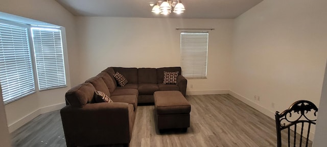 living room featuring a notable chandelier, wood finished floors, and baseboards