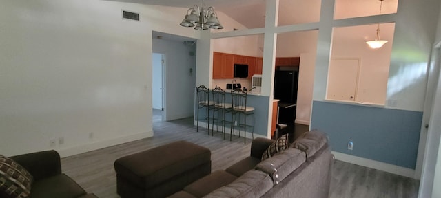 living area with baseboards, visible vents, a chandelier, wood finished floors, and high vaulted ceiling