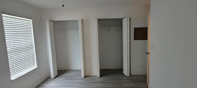 unfurnished bedroom featuring multiple windows, multiple closets, and wood finished floors