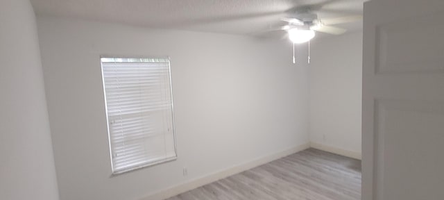 spare room featuring light wood-style floors, ceiling fan, and baseboards