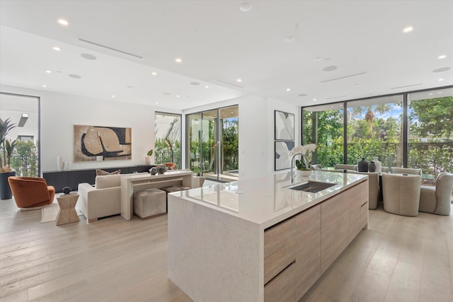 kitchen with light wood-type flooring, modern cabinets, open floor plan, and a sink