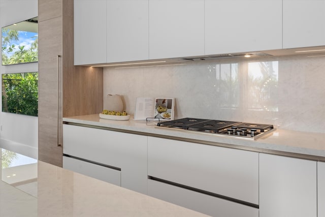 kitchen featuring tasteful backsplash, stainless steel gas stovetop, and white cabinets