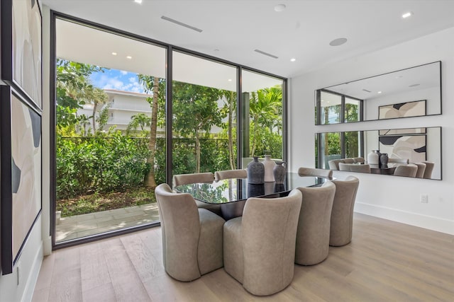 dining room featuring a wall of windows, visible vents, baseboards, and wood finished floors