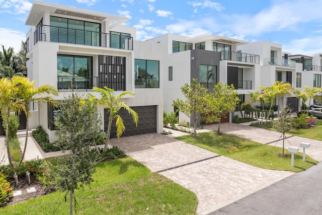 view of front of home with decorative driveway, a garage, and stucco siding