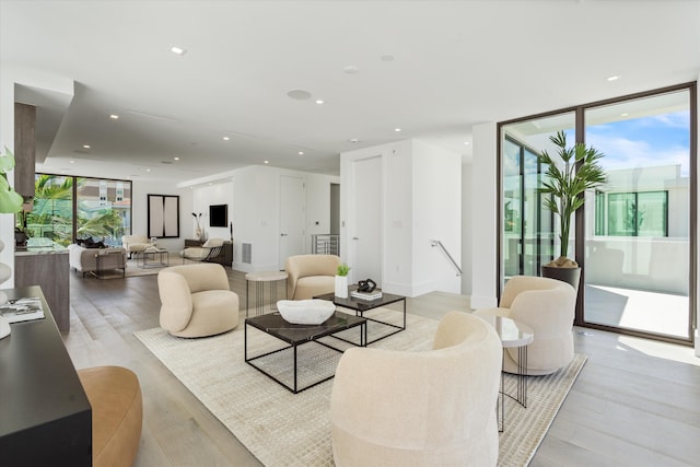 living room with expansive windows, light wood-type flooring, visible vents, and recessed lighting