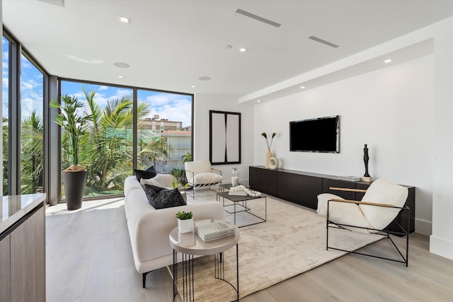 living area featuring baseboards, visible vents, light wood-style flooring, expansive windows, and recessed lighting