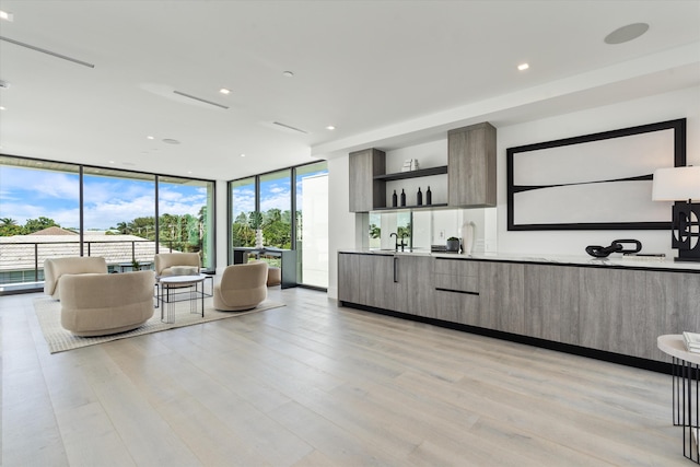 kitchen featuring modern cabinets, open floor plan, a wall of windows, open shelves, and a sink